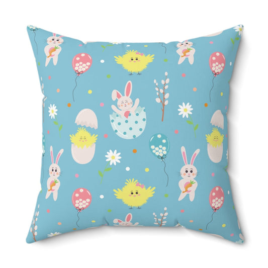 A square decorative pillow with a pattern of playful bunnies, eggs, and spring flowers on a blue background.