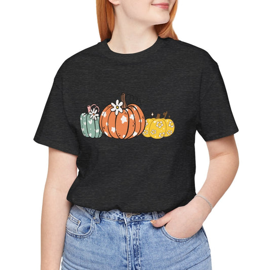 Person wearing a black t-shirt with colorful pumpkins and blue jeans on a white background