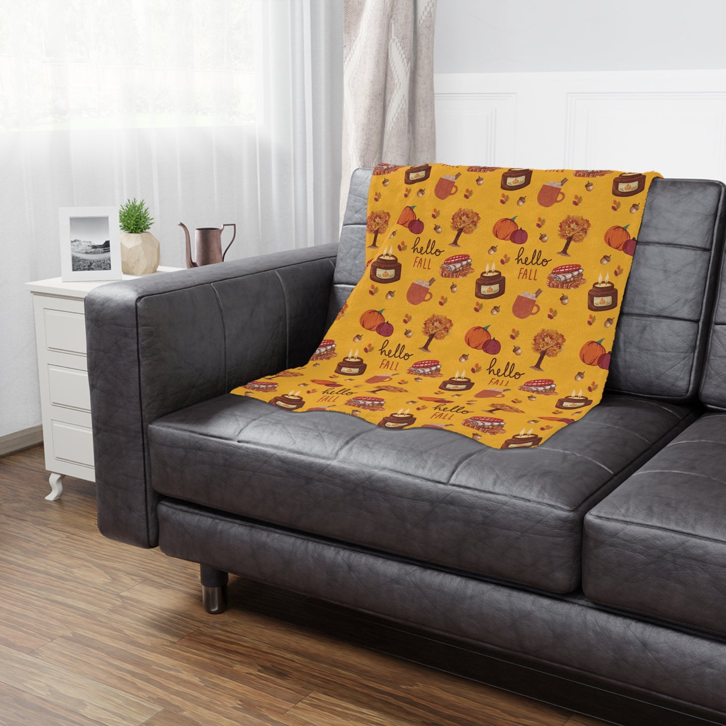Yellow minky blanket with autumn-themed design on a gray sofa in a living room.