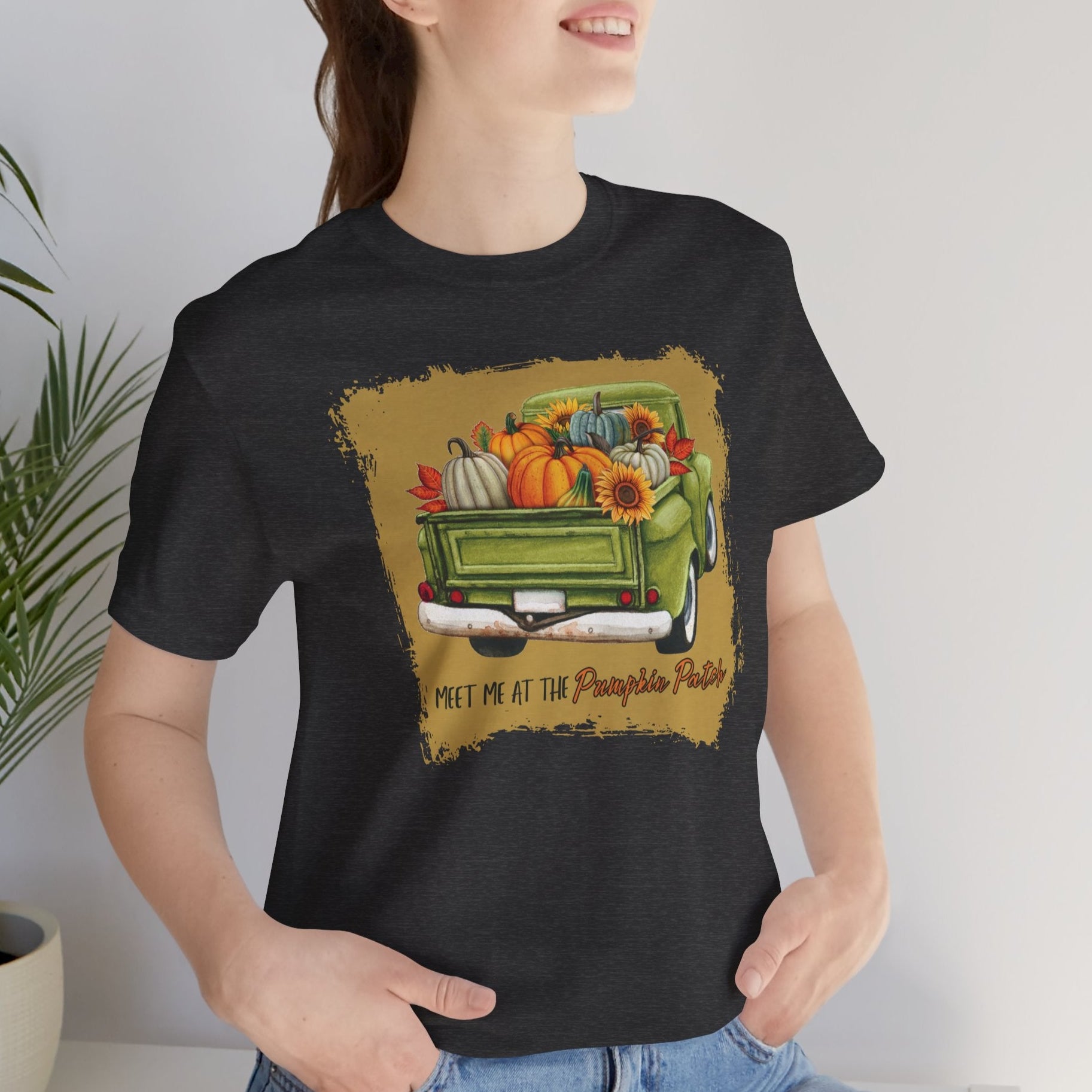 Person wearing a black t-shirt with a graphic of a green truck filled with autumn items and text.