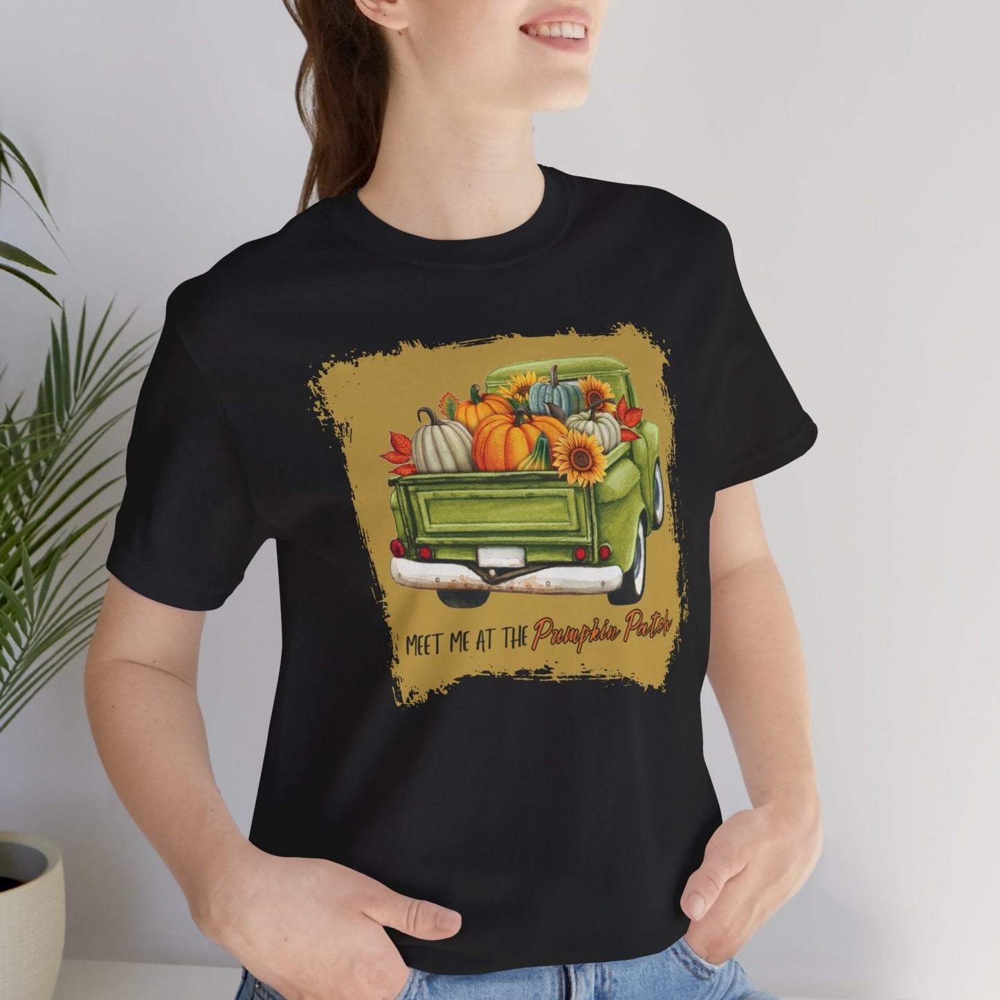 Person wearing a black t-shirt with a graphic of a green truck filled with autumn items and text.