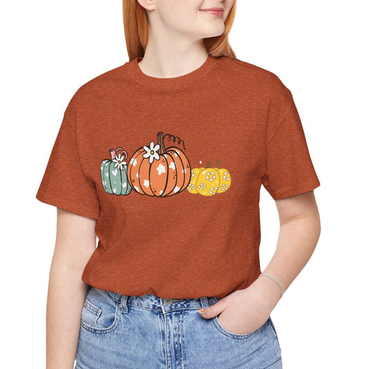 Person wearing a brown t-shirt with pumpkin design on a white background