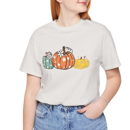 Person wearing a white t-shirt with colorful pumpkin design and blue jeans on a white background