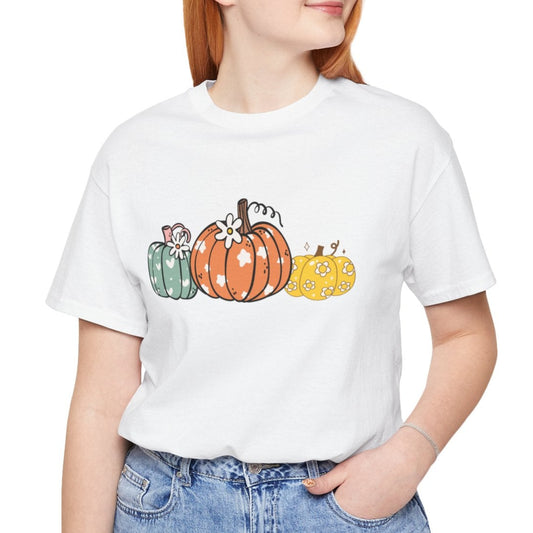 Person wearing a white t-shirt with colorful pumpkins and blue jeans on a white background
