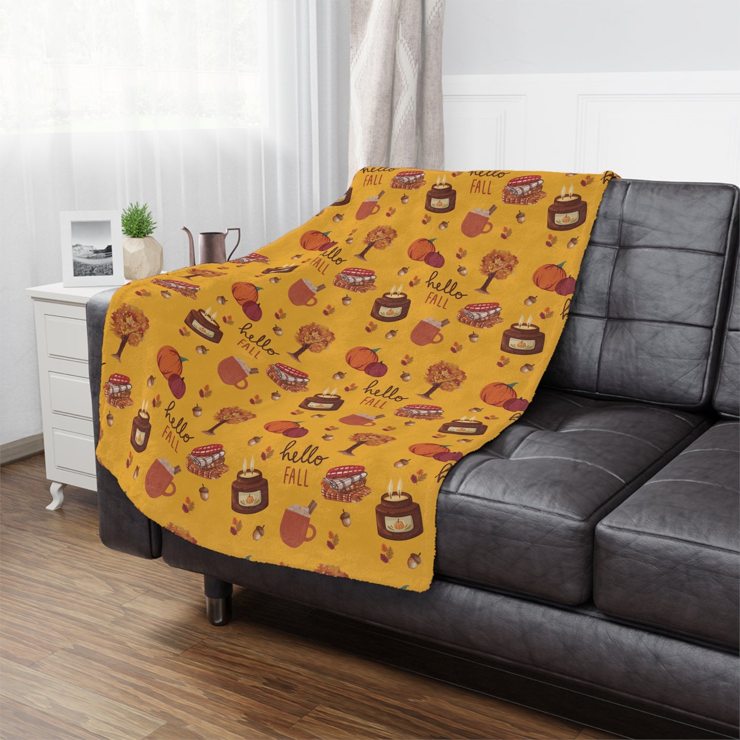 Yellow 'Hello Fall' patterned minky blanket draped over a gray sofa in a living room.