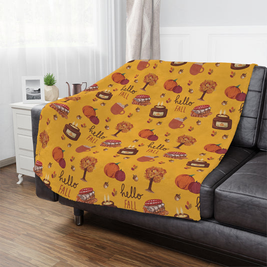 Yellow 'hello fall' patterned minky blanket draped over a gray sofa in a living room.