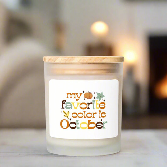 Candle with a label reading 'my favorite color is October' in a cozy setting.