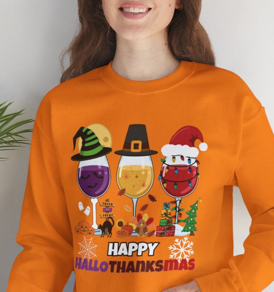 Person wearing an orange sweatshirt with 'Happy HalloThanksMas' design, sitting on a white surface with a plant in the background.