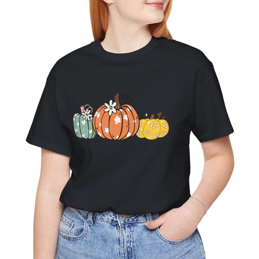 Person wearing a black t-shirt with colorful pumpkins and blue jeans on a white background