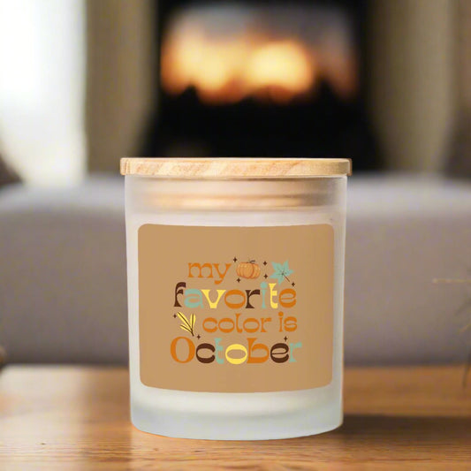 Candle with a decorative label reading 'my favorite color is October' on a wooden surface.
