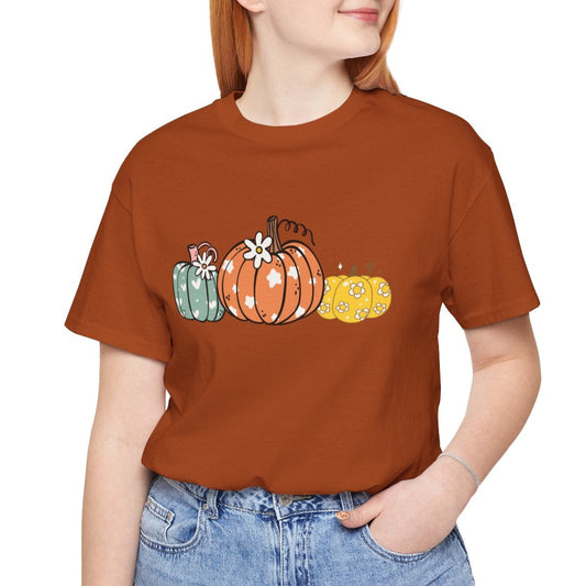 Person wearing a brown t-shirt with pumpkin design on a white background
