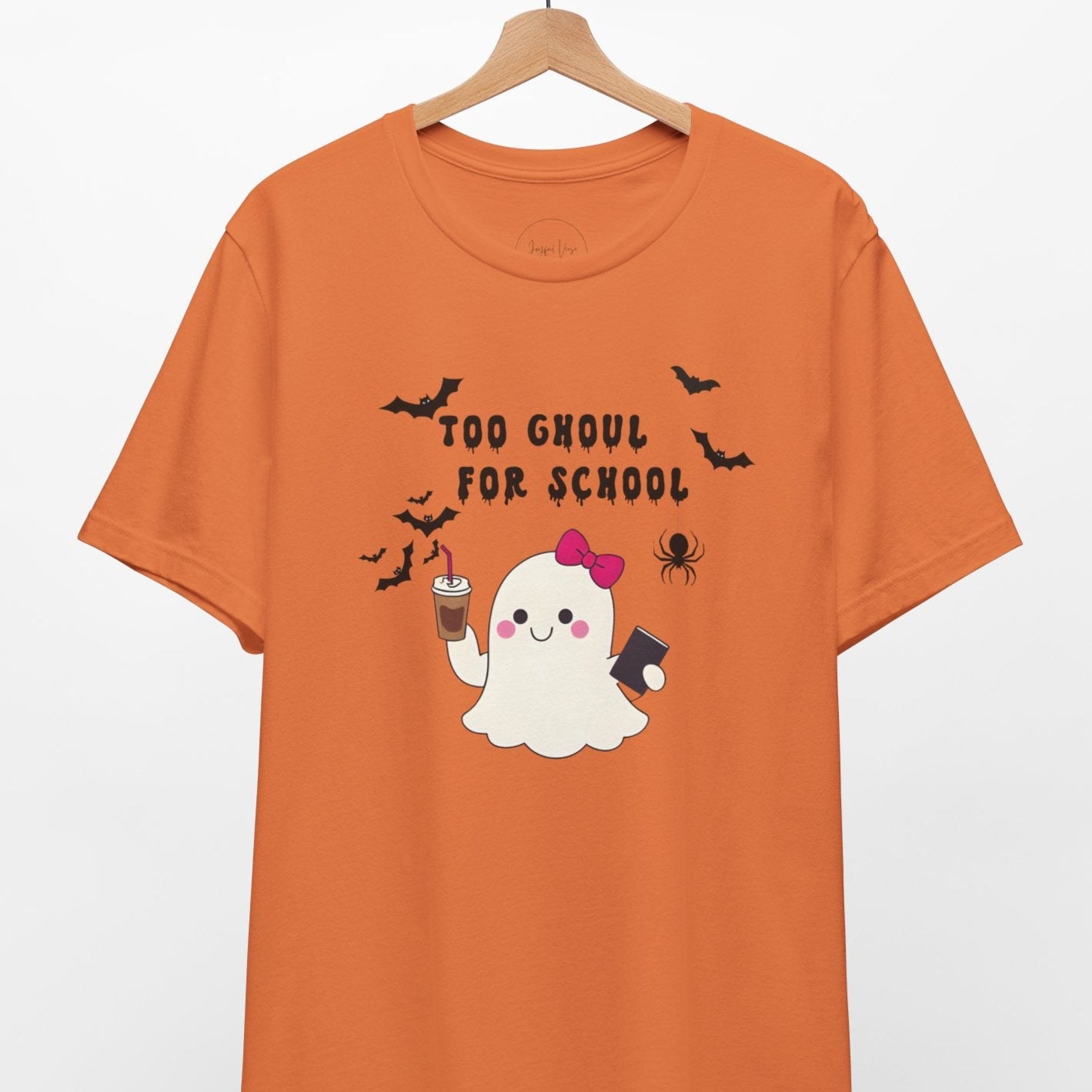 Orange t-shirt with Halloween-themed design featuring a ghost and text on a hanger against a white background.
