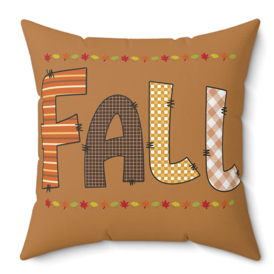 Brown fall pillow with stitched “FALL” letters in plaid and gingham patterns, accented with autumn leaves.