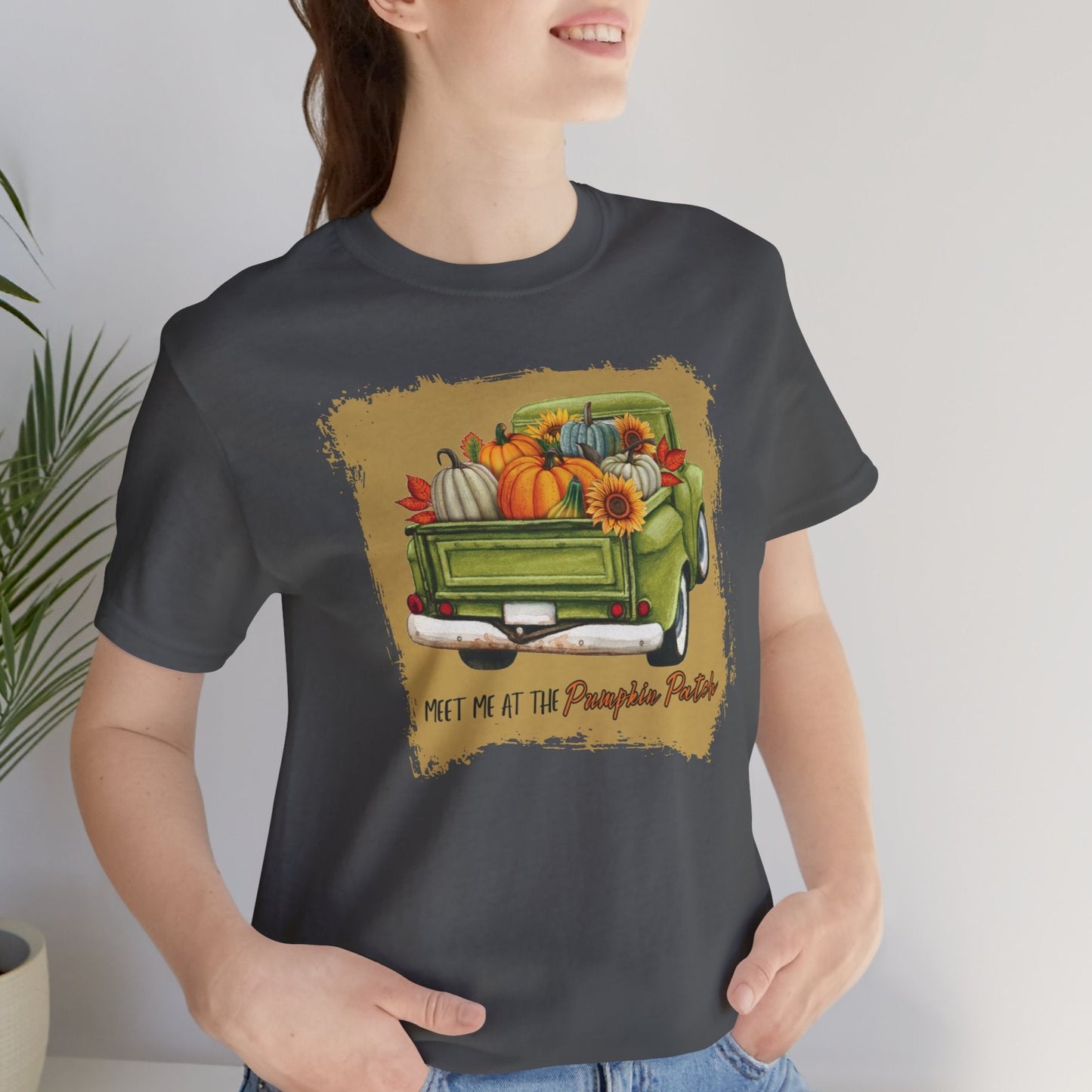 Person wearing a grey t-shirt with a graphic design of a truck and pumpkins.