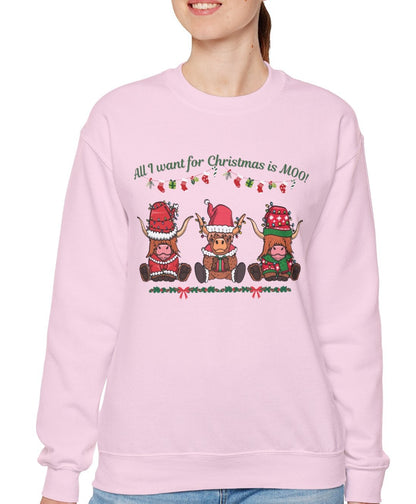 Woman wearing a pink sweatshirt with "All I Want for Christmas Is MOO" sweatshirt featuring three festive cows wearing Santa hats and scarves, printed on cozy crewneck sweaters in white and pink. Exclusive Joyful Verse design by Sara.