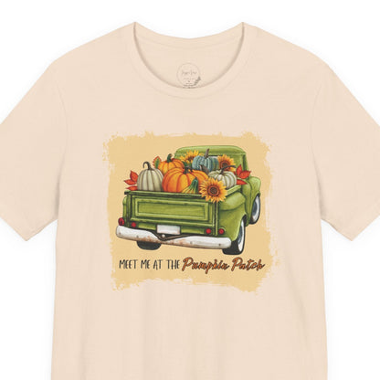 Beige t-shirt with a graphic of a green truck and pumpkins on a white background