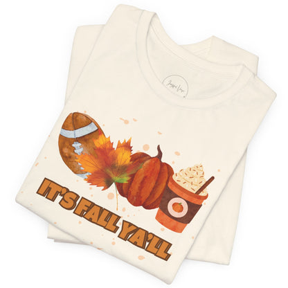 Folded cream colored t shirt with autumn-themed design and text 'It's Fall Ya'll' on a white background