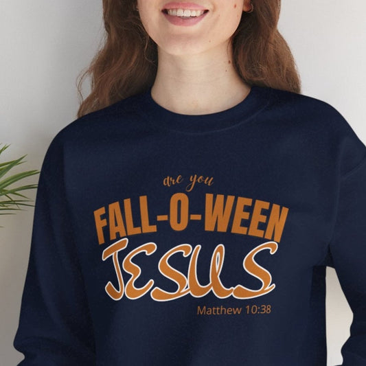 Person wearing a navy sweatshirt with 'Fall-o-ween Jesus' text, sitting against a white wall with a plant.