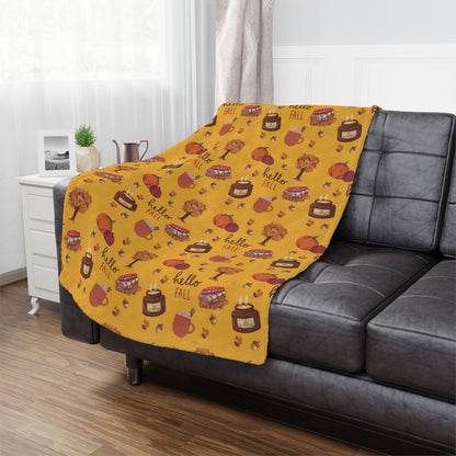 Yellow 'Hello Fall' patterned minky blanket draped over a gray sofa in a living room.