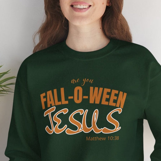 Person wearing a green sweatshirt with 'Fall-o-ween Jesus' text, sitting on a white surface with a plant in the background.