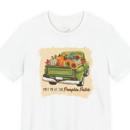 White t-shirt with a graphic of a green truck carrying pumpkins and flowers, with text 'Meet me at the Pumpkin Patch' on a white background.