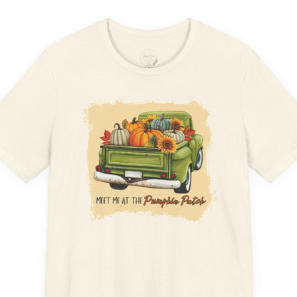Beige t-shirt with a graphic of a green truck carrying pumpkins and flowers, with text 'Meet me at the Pumpkin Patch' on a white background.