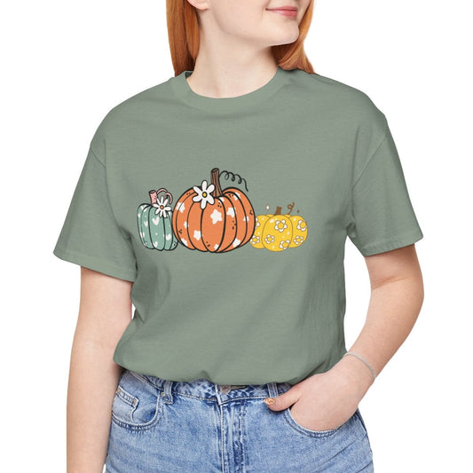 Person wearing a green t-shirt with pumpkins and blue jeans on a white background