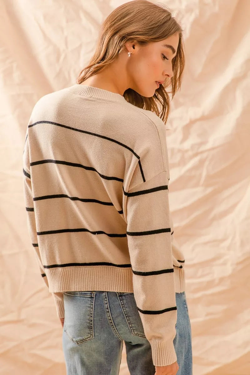 Woman wearing a beige sweater with black stripes against a beige background