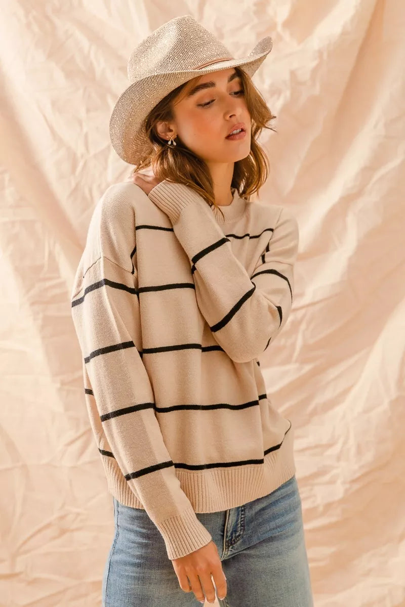 Woman wearing a striped sweater and cowboy hat against a beige background