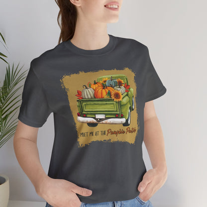 Person wearing a grey t-shirt with a graphic design of a truck and pumpkins.