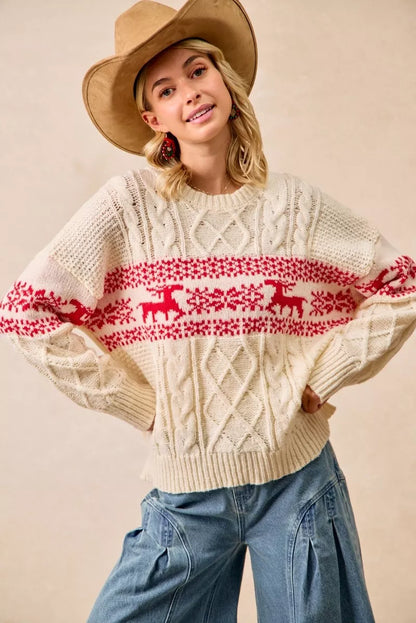 Woman wearing a cream sweater with red deer pattern and a wide-brimmed hat on a beige background