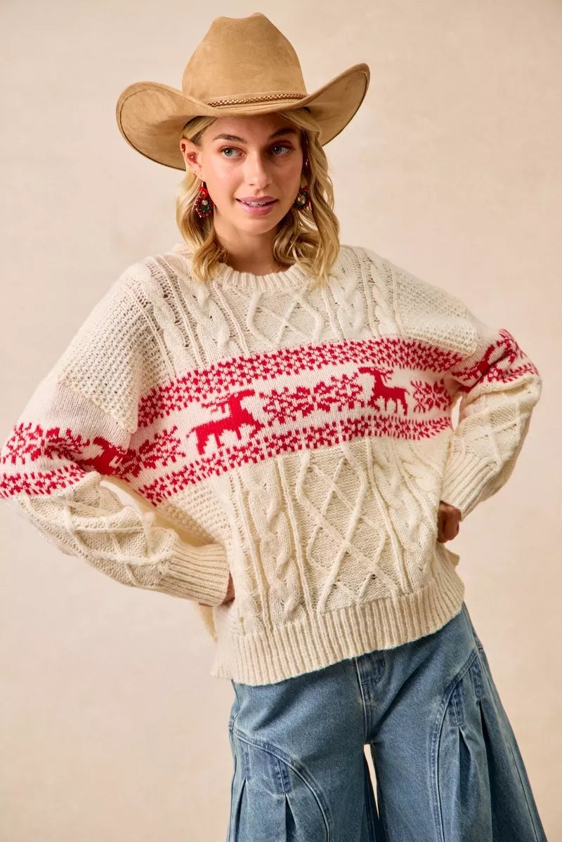 Christmas-themed cable knit sweater with festive red and white holiday pattern on a female model.